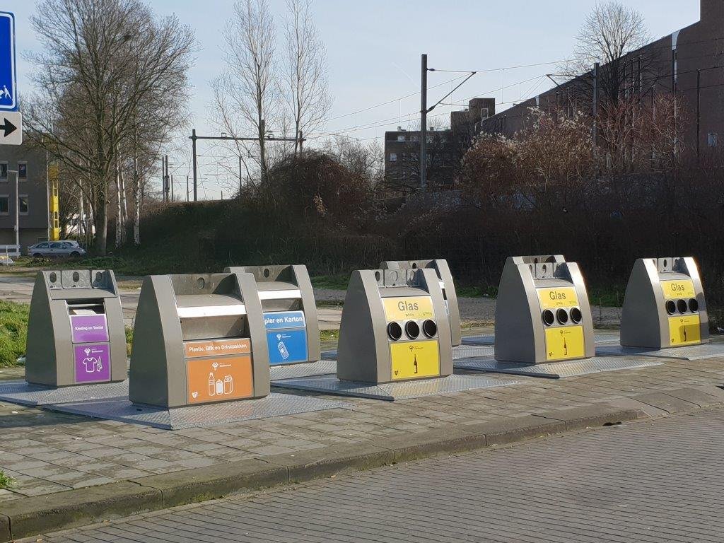 foto van een milieu eiland met containers voor glas, plastic en papier